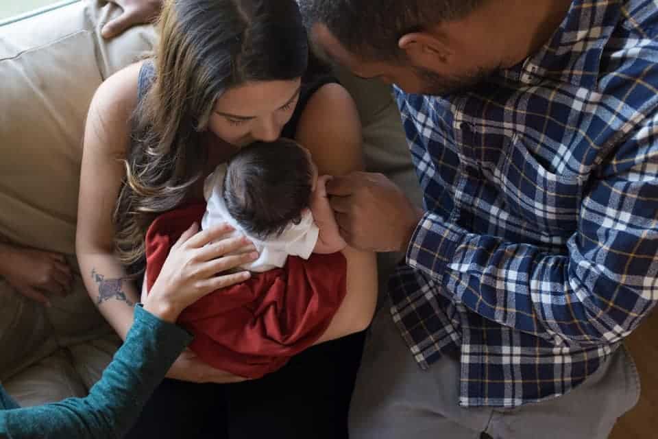 family sitting holding newborn baby