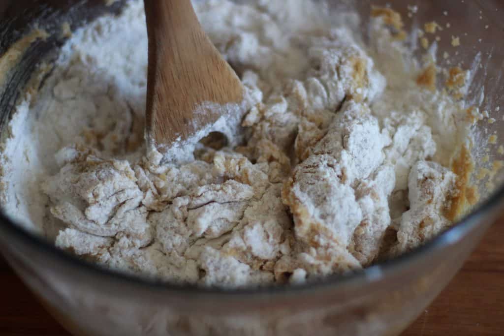 wooden spoon mixing together wet and dry ingredients for cookie dough