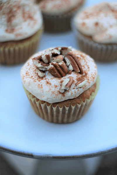 carrot cake cupcake with cream cheese frosting, cinnamon, & crushed pecans