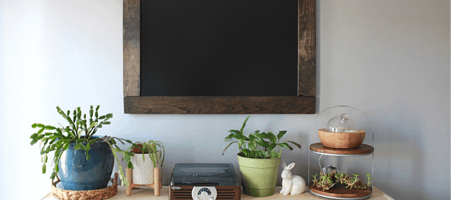 DIY Chalkboard hanging on wall above wooden shelf with plants on it