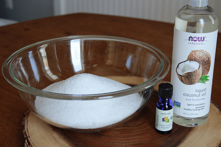 glass bowl full of epsom salt with bottles of liquid coconut oil and lavender essential oils sitting next to it