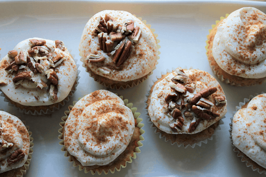 7 carrot cake cupcakes with cream cheese frosting, cinnamon, & crushed pecans on top