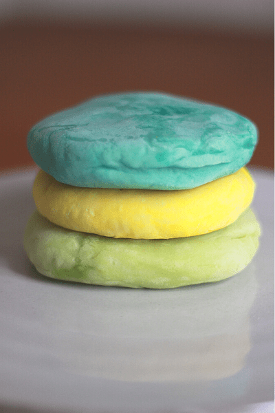green yellow and blue homemade playdough stacked on top of eachother on tray