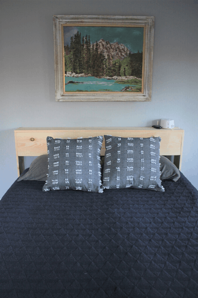 diy headboard shelf with queen size bed in front with blue blanket on top with grey pillows on bed