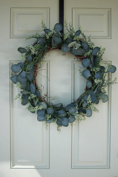 DIY eucalyptus wreath hanging on a light green front door