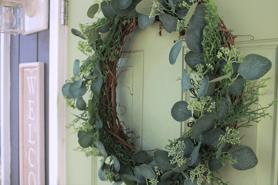 DIY eucalyptus wreath hanging on a light green front door 
