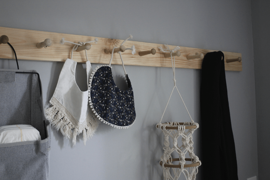 DIY shaker peg rail hanging on the wall with baby items on it