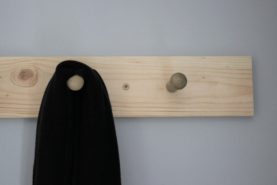 DIY shaker peg rail mounted on the wall with two and a half inch screws and a baby wrap hanging on it 