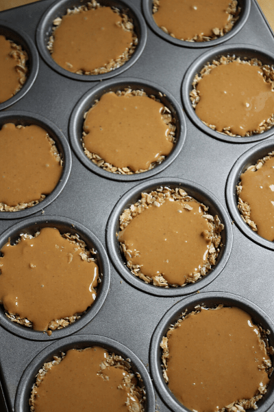 no bake oat cups in 12 cupcake tins with melted cashew butter spread on top
