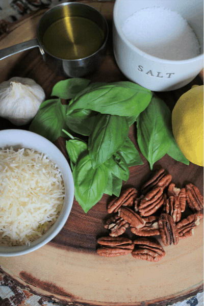 ingredients for easy pesto recipe measured out on a wooden cutting board
