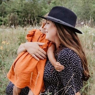 toddler hugging mother sitting on a the ground in a field