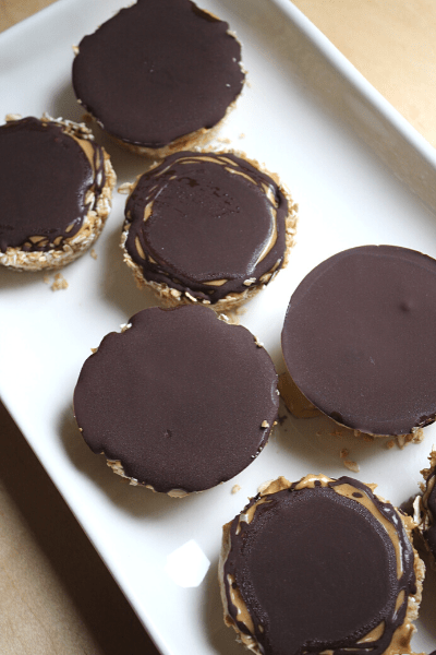 no bake oat cups with cashew butter and dark chocolate on top displayed on a long white dish