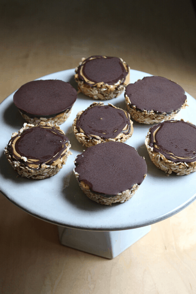 no bake oat cups with cashew butter and dark chocolate spread out and displayed on a grey cake stand