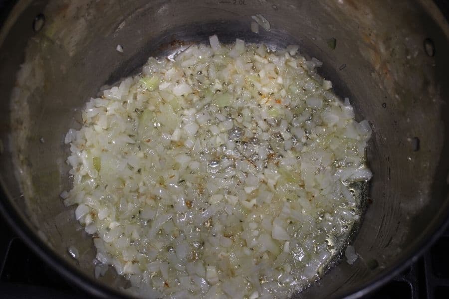 white onions sauteing in butter in a large stainless steel pot