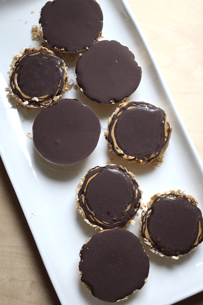seven no bake oat bites with cashew butter and dark chocolate melted on top spread out on a long white plate